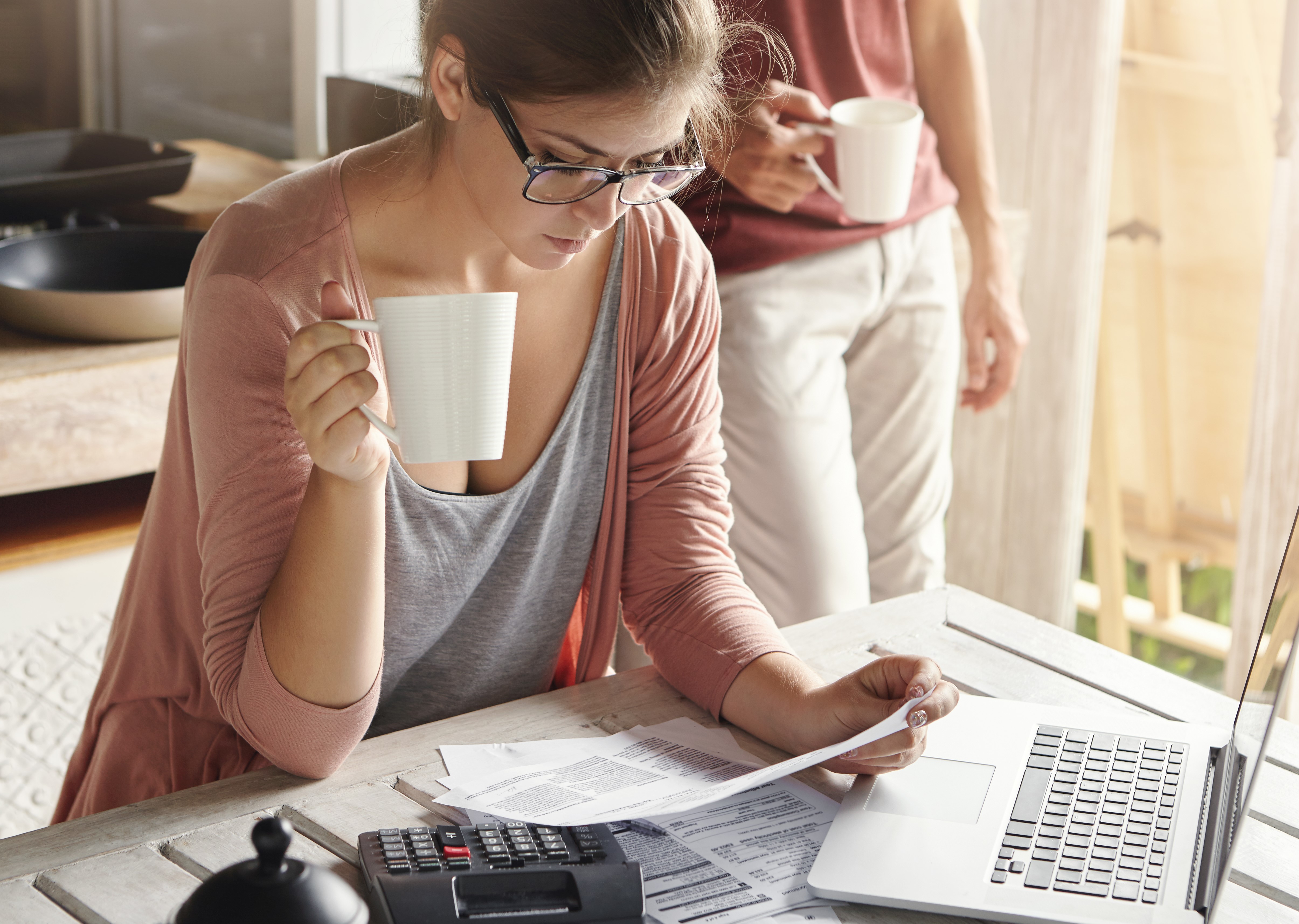 young-female-drinking-tea-studying-bill-her-hands-having-frustrated-look-while-managing-family-budget-doing-paperwork-sitting-kitchen-table-with-papers-calculator-laptop-computer.jpg?Revision=Z6M&Timestamp=rfGxsk